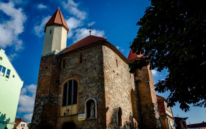 Kościół z wysoką wieżą pośród zielonych wzgórz