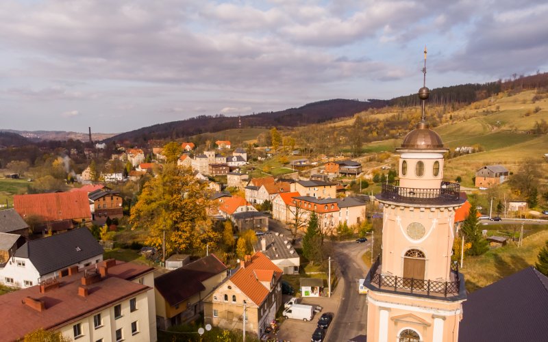 Panorama miasta z kościołem i kamienicami na tle wzgórz