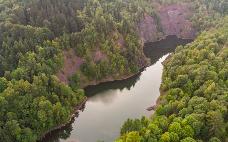 Zbiornik wodny wśród zalesionych wzgórz widziana z lotu ptaka
