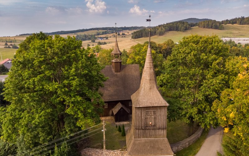 Drewniany kościół otoczony zielenią i drzewami