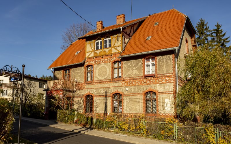 Zabytkowy budynek z czerwonym dachem i ozdobną ceglaną elewacją