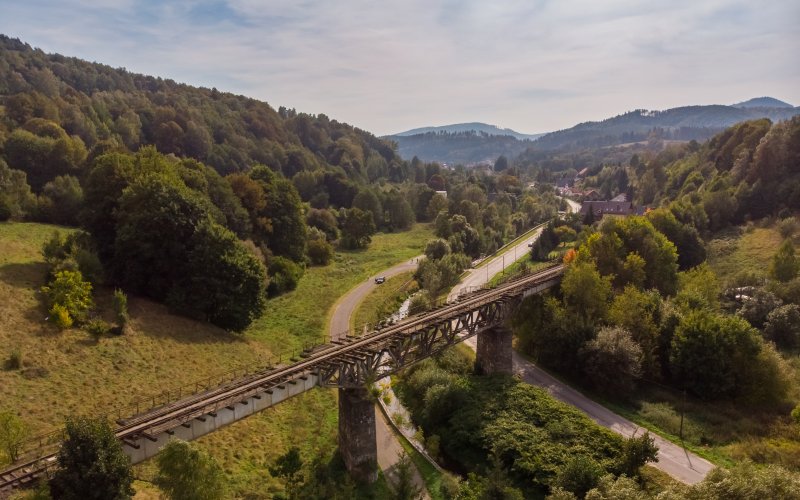 Most kolejowy nad doliną otoczoną lasami i wzgórzami