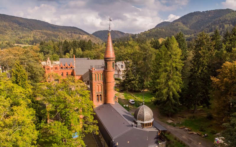 Kościół z wysoką wieżą pośród zielonych wzgórz