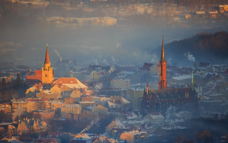 Panorama starego miasta z kościołami i dachami kamienic o zachodzie słońca