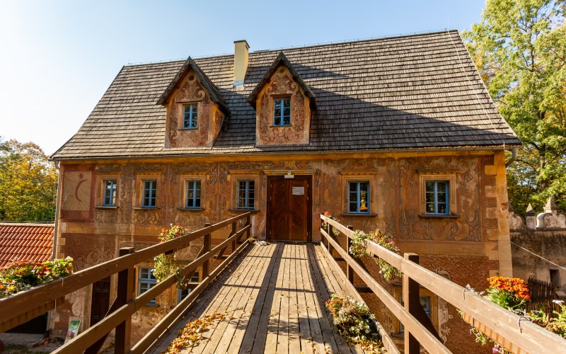 Zabytkowy dom z bogato zdobioną elewacją i drewnianym mostkiem prowadzącym do wejścia